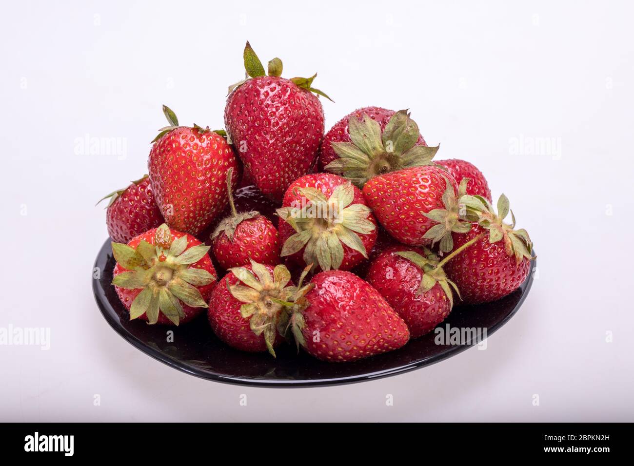 fresh ripe strawberries on black plate isolated on white background ...