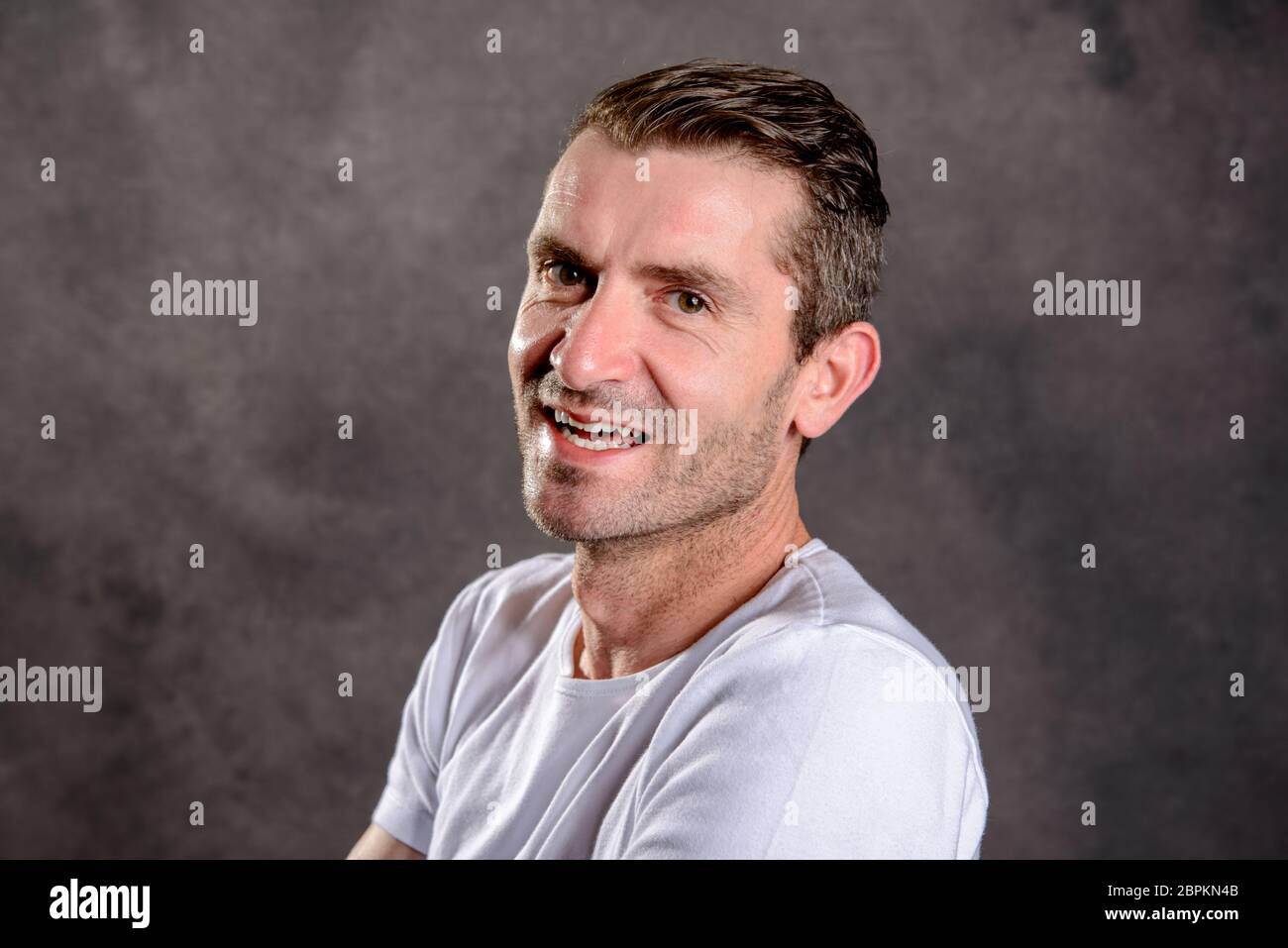 friendly young man with crossed arms in front of gray background Stock ...