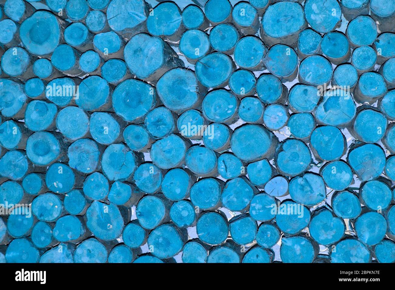 Abstract background pattern image manipulated blue colour applied to ends of stacked short lengths random diameter round sawn timber logs England UK Stock Photo