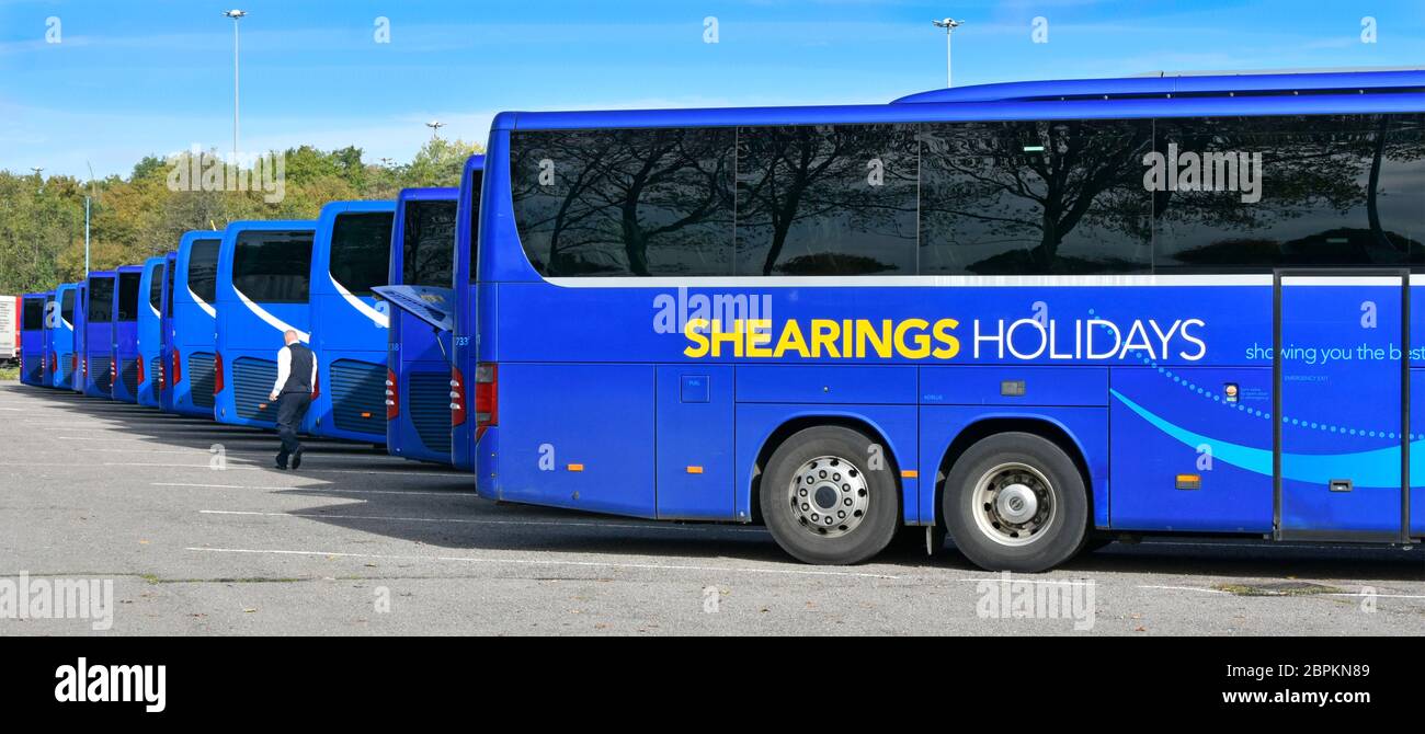 Repetition view side & rear end of blue touring & travel coaches operated by Shearings Holidays parked at feeder coach interchange London England UK Stock Photo