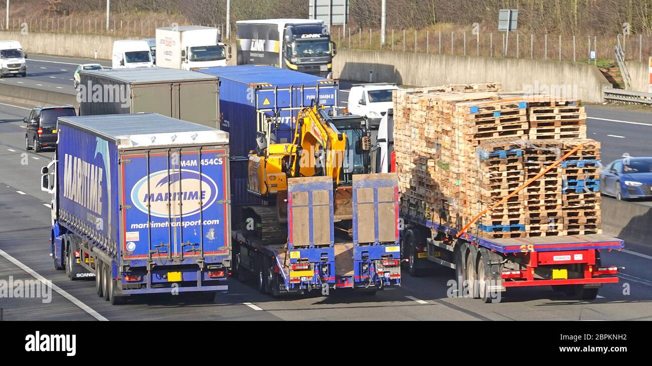 Bunched up medium lens view of back of hgv lorry truck & articulated trailer driving along close together in 3 lanes on UK motorway Essex England UK Stock Photo