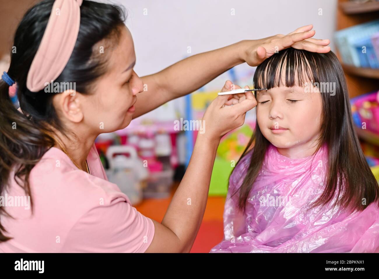 Asian Mother cutting hair to her daughter at home while stay at home safe from Covid-19 Coronavirus during lockdown city. Self-quarantine and social Stock Photo