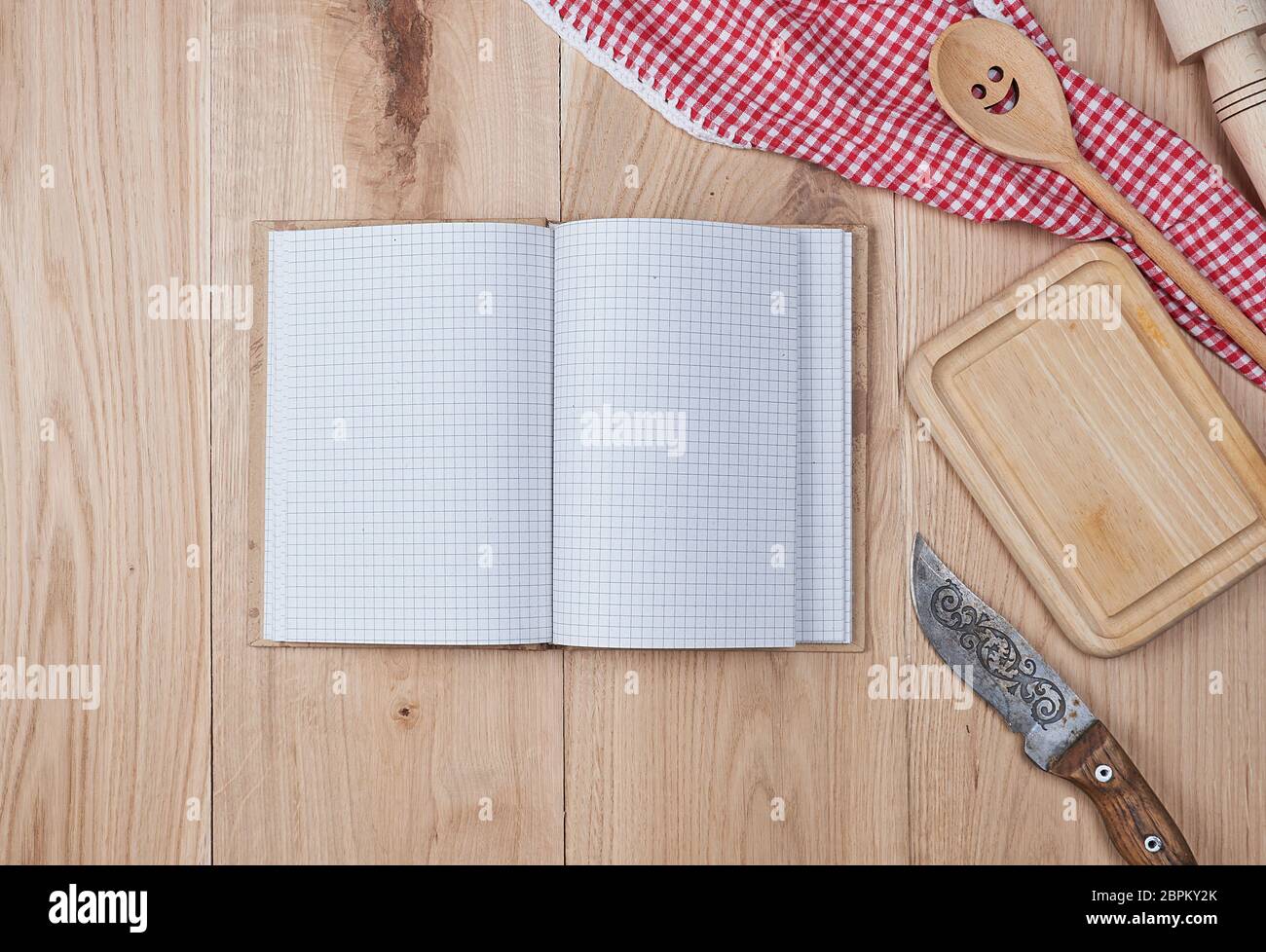 open empty notebook with white sheets and a kitchen wooden spoon on the table, top view Stock Photo