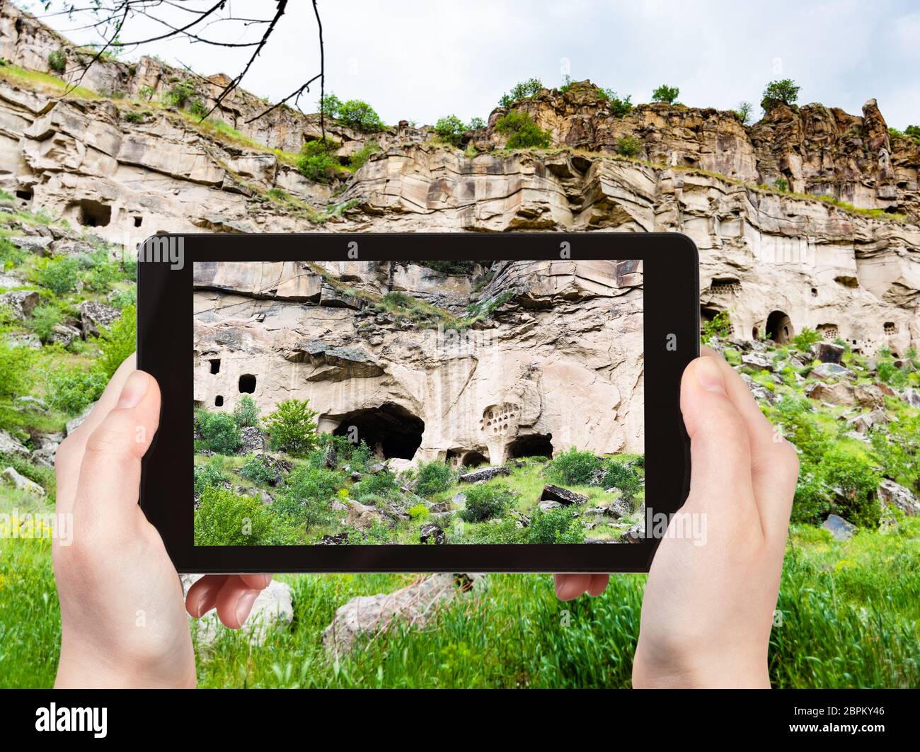 travel concept - tourist photographs of rock-cut caves in Ihlara Valley of Aksaray Province in Cappadocia on smartphone in Turkey in spring Stock Photo