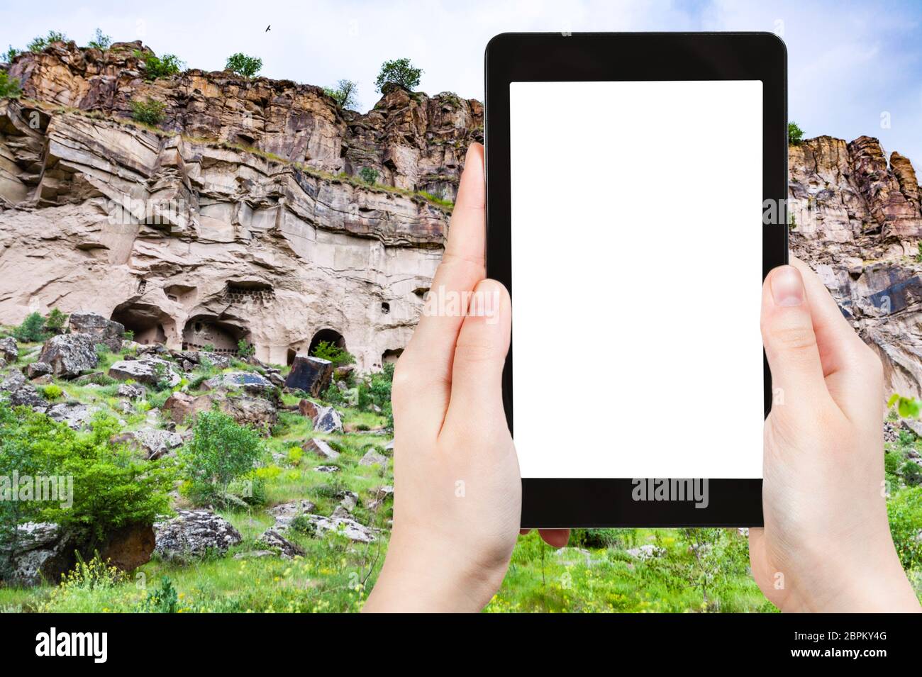 travel concept - tourist photographs of rocks caves in Ihlara Valley of Aksaray Province in Cappadocia in spring in Turkey on smartphone with empty cu Stock Photo