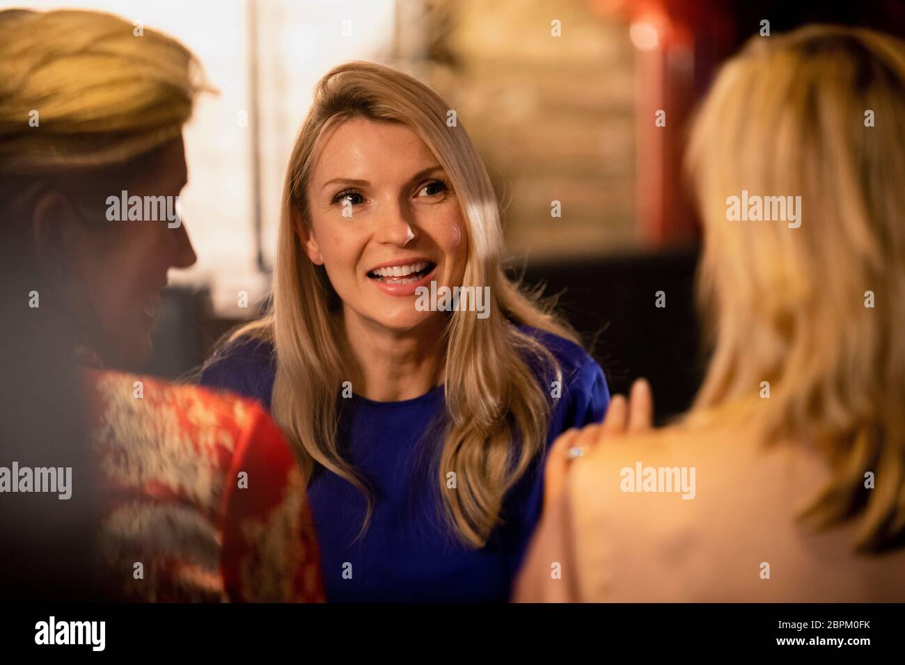 Over the shoulder view of a mature woman talking and smiling with her friends. Stock Photo