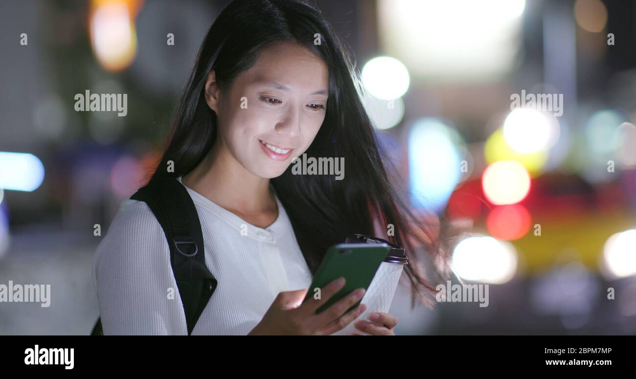Woman look at the mobile phone in city at night Stock Photo - Alamy
