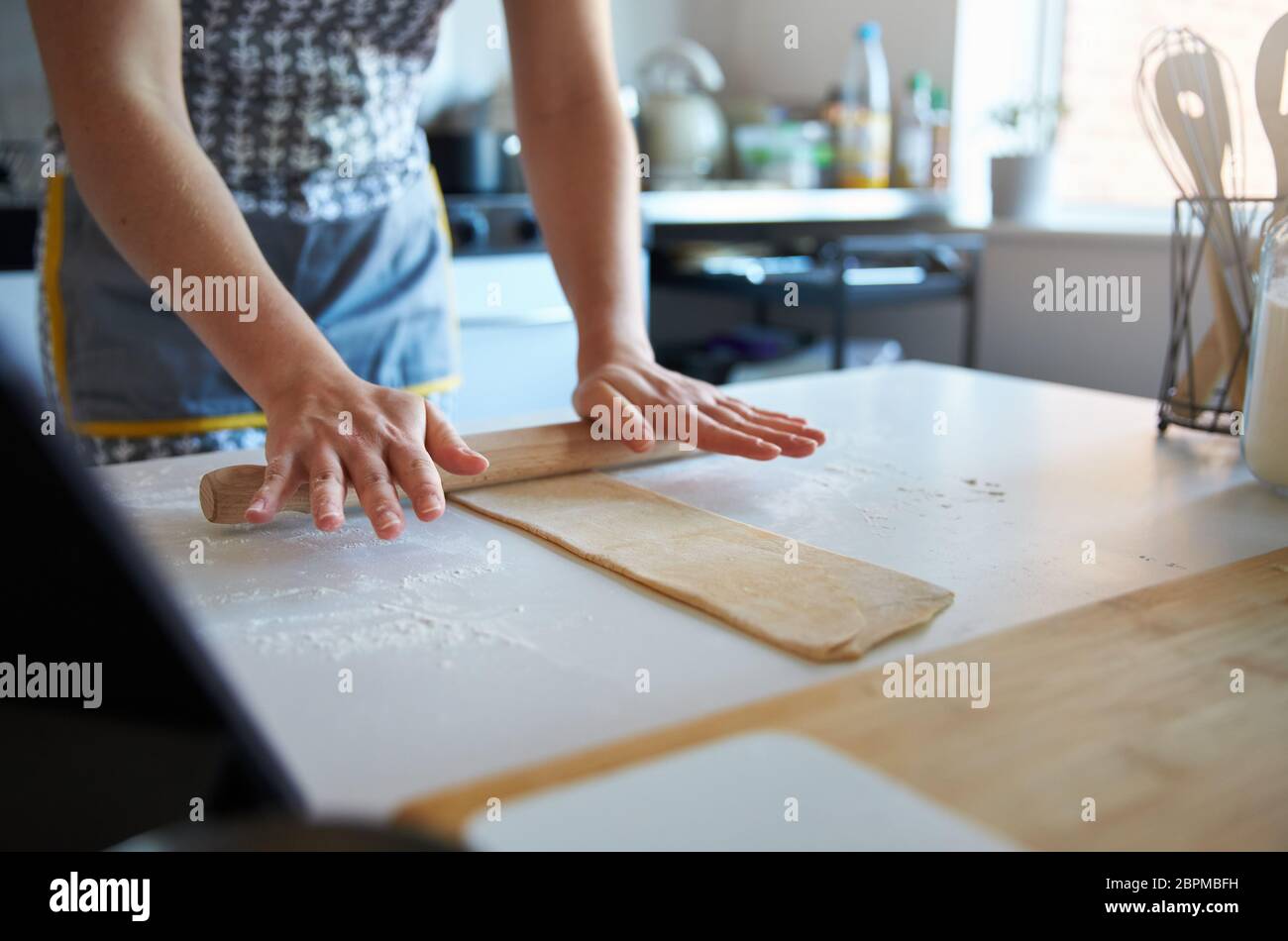 Anonymous person using a rolling pin to make fresh pasta at home. Stock Photo