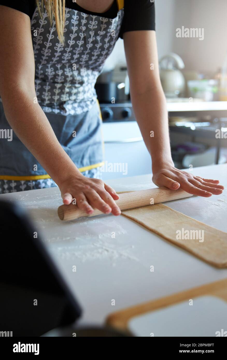 Anonymous person using a rolling pin to make fresh pasta at home. Stock Photo