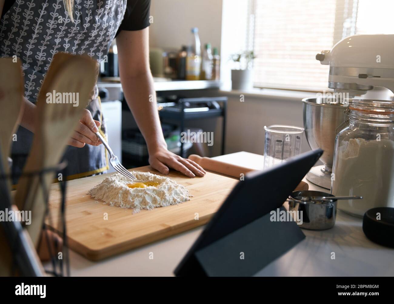 Anonymous Person Making Fresh Pasta At Home in The Kitchen, Watching A Video Recipe with eggs and flour. Stock Photo