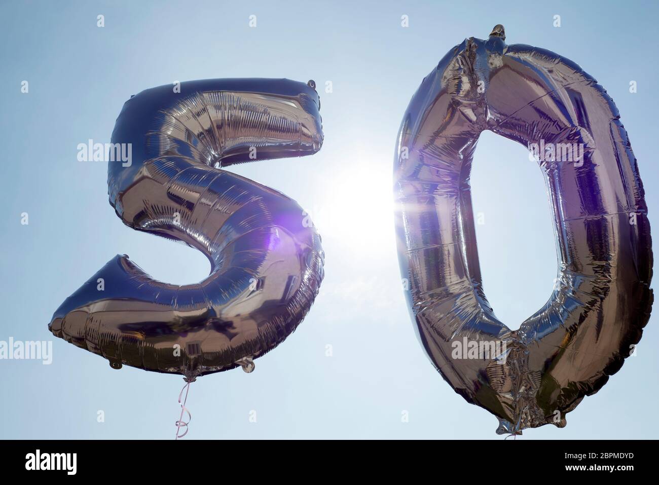 silver balloons for a 50th anniversary floating among the clouds Stock Photo