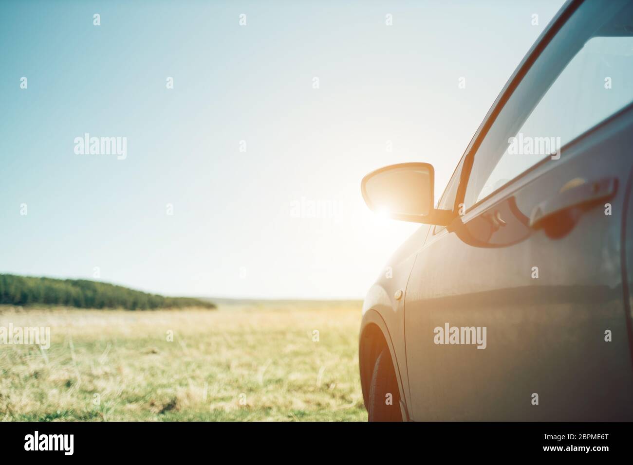Beautiful car in nature in the sun, field and forest with sky Stock Photo