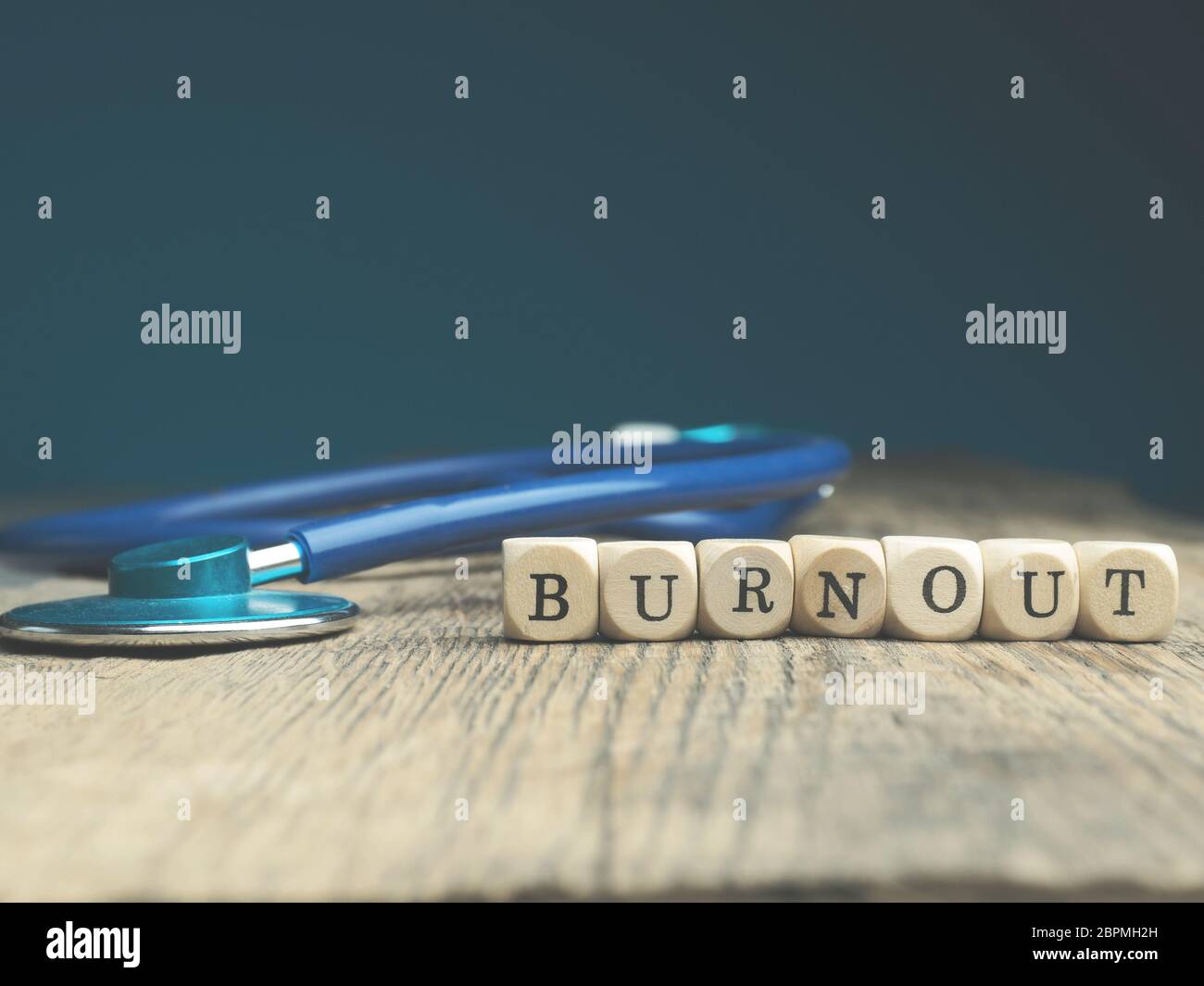 The word burnout on small wooden blocks with a stethoscope on a wooden ...