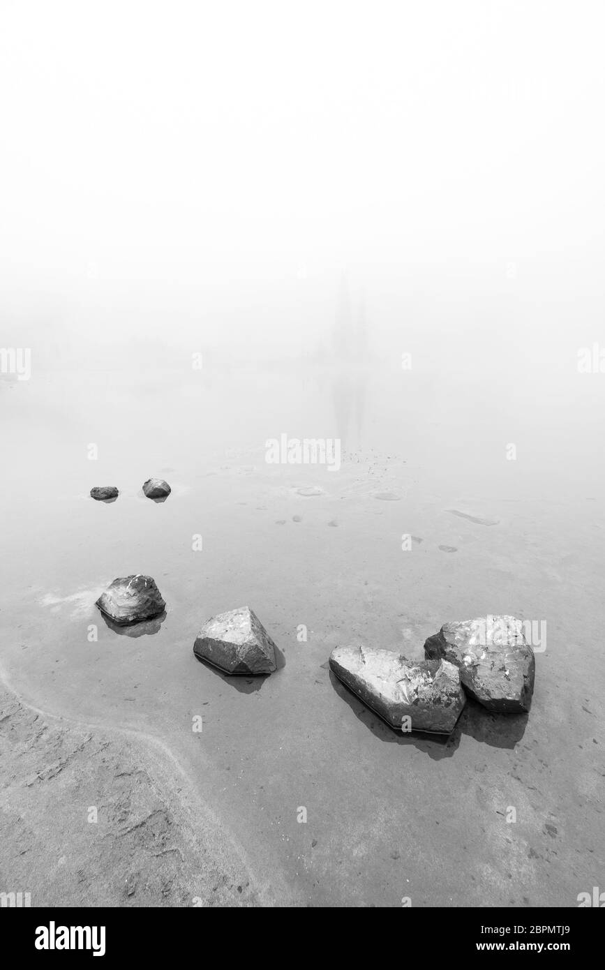 peaceful rock,rock in the lake with fog over the lake in black and white.. Stock Photo