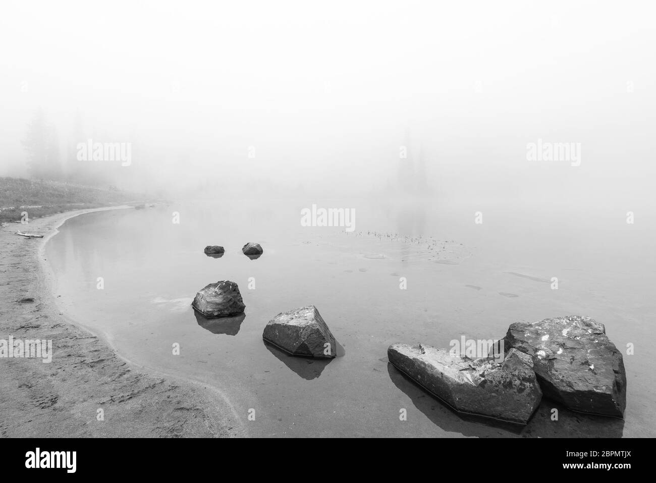 peaceful rock,rock in the lake with fog over the lake in black and white.. Stock Photo