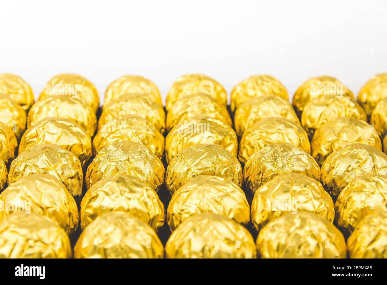 a lot of shiny golden chocolate wrapper in line on white