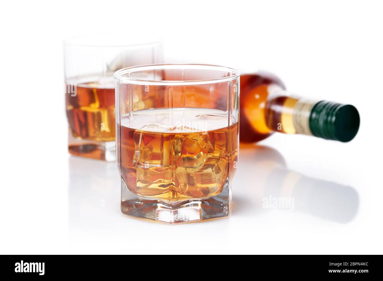 Bottle of whisky and two glasses of whisky with ices on a white background with reflection Stock Photo