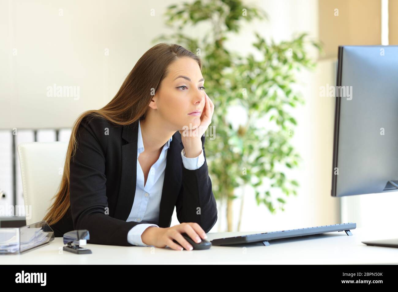 Confused and bored office worker checking computer content at workplace Stock Photo