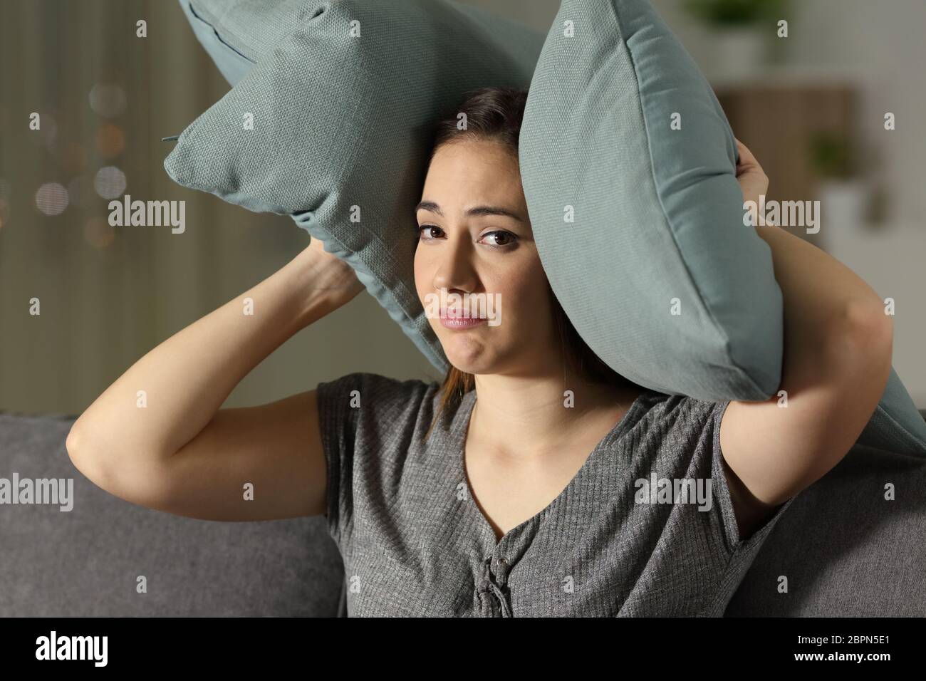Desperate woman covering ears to protect from neighbour noise sitting