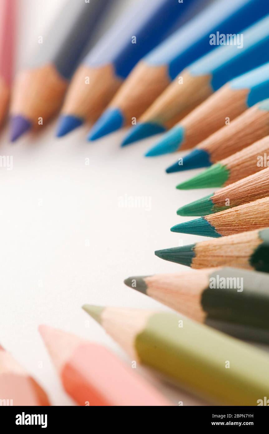 Close up semicircular crayons in blue and green tones on white background. Stock Photo