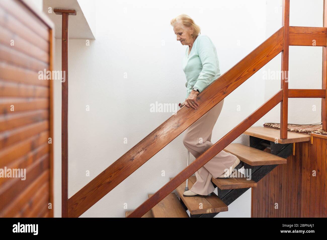 Elderly woman at home using a walking cane to get down the stairs Stock Photo Alamy