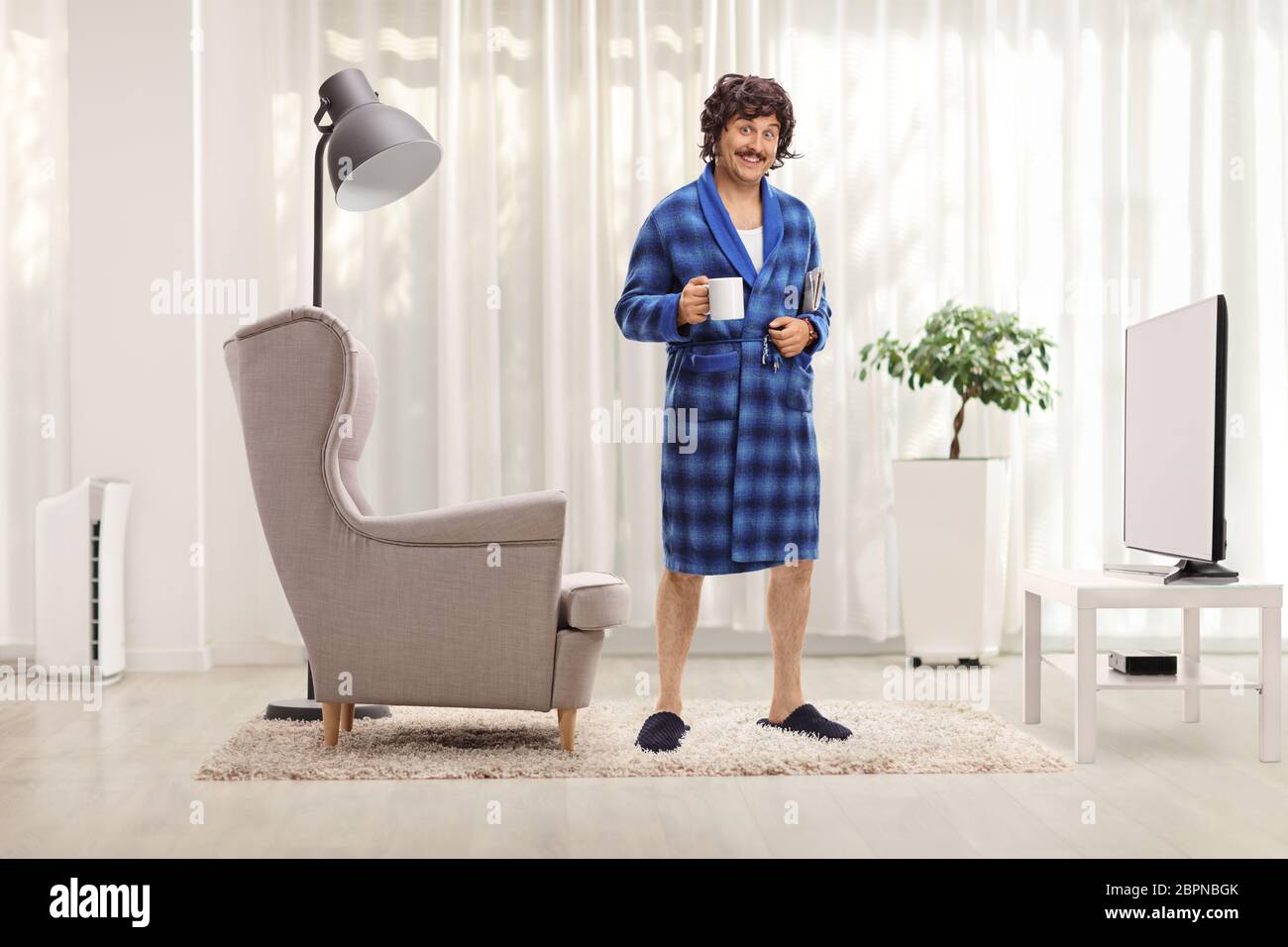 Funny man in a blue bathrobe holding a cup at home in a living room Stock  Photo - Alamy