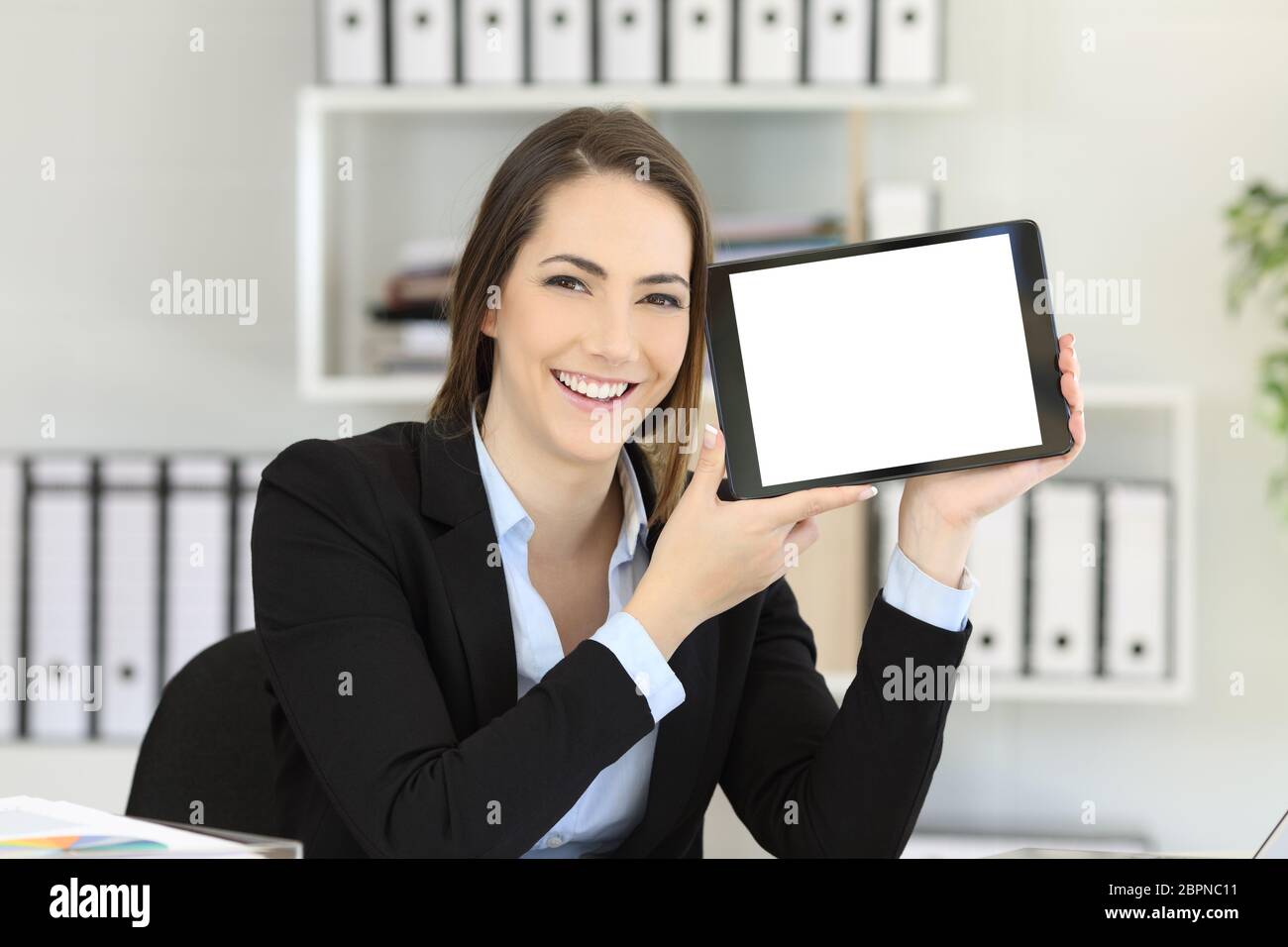 Happy office worker showing an horizontal tablet screen mock up Stock Photo