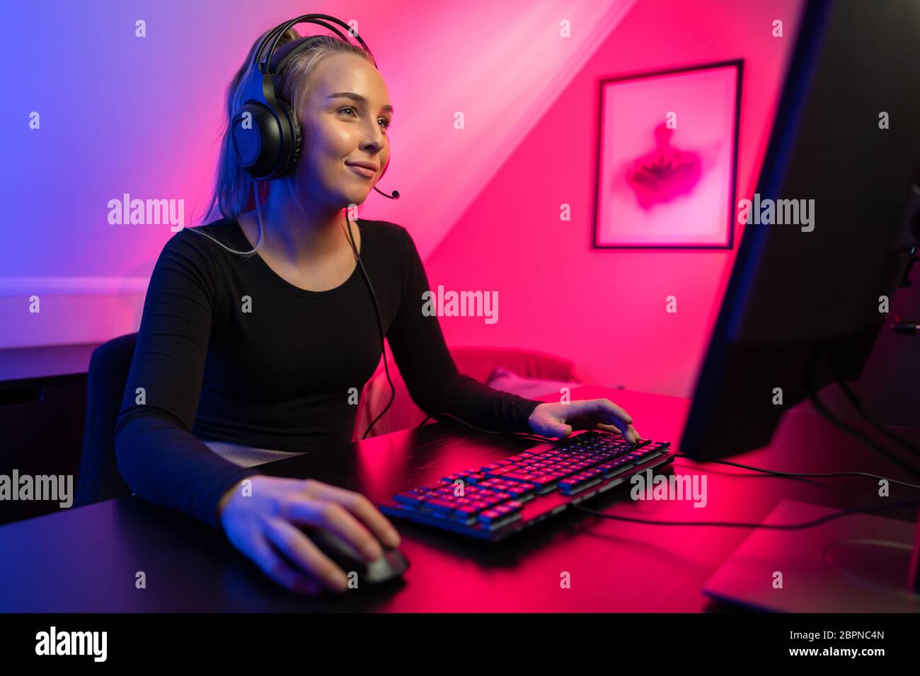 Happy asia girl gamer wear headphone competition play video game online  with smartphone colorful neon lights in living room at home. Esport  streaming game online, Home quarantine activity concept. Stock Photo