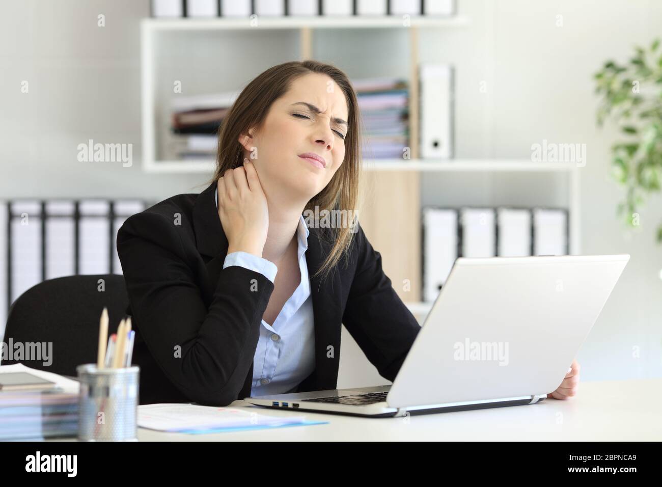 Office worker suffering neck ache sitting in a desktop Stock Photo - Alamy