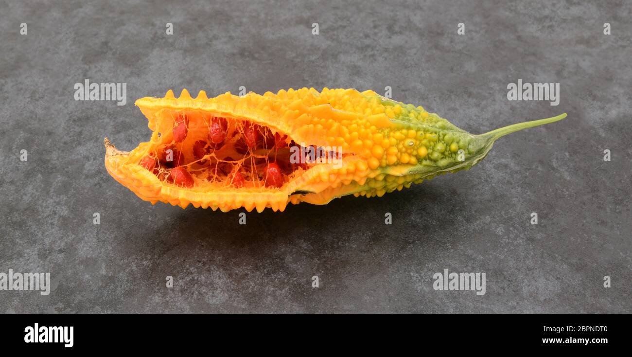 Orange bitter gourd, with ridged flesh, split open to show red seeds
