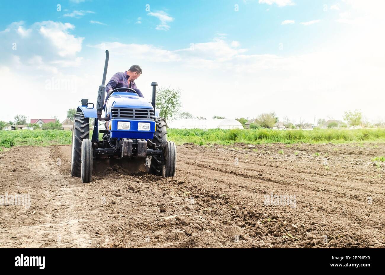 Farmer is processing soil on a tractor. Soil milling, crumbling mixing