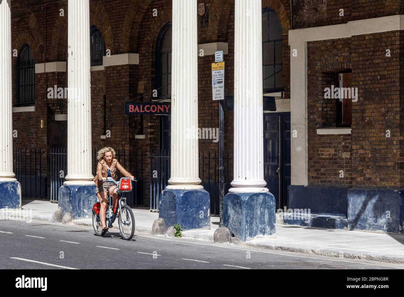 A cyclist passes the colonnade of the Theatre Royal Drury Lane, closed  during the coronavirus pandemic lockdown, London, UK Stock Photo