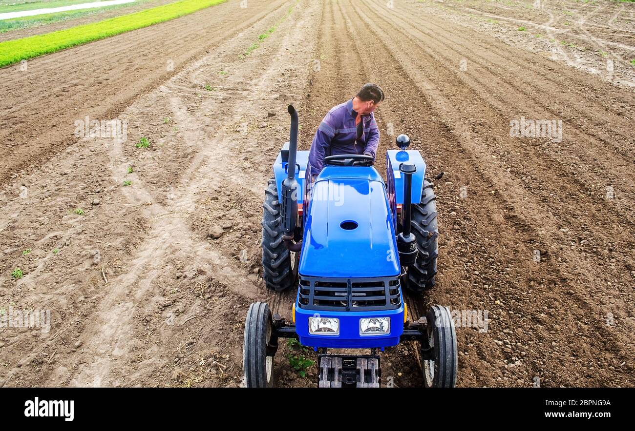 A farmer on a tractor cultivates a farm field. Soil milling, crumbling ...