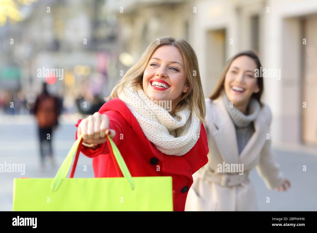 Two happy shoppers running searching shops outdoor on the street Stock Photo