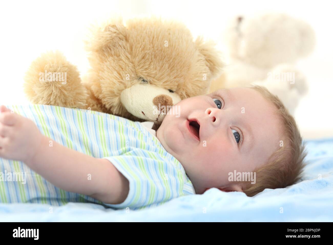 Happy baby and teddy bear lying on a bed Stock Photo - Alamy