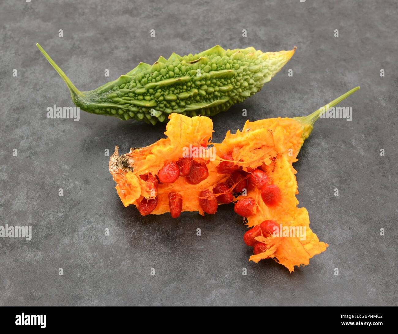Green, ridged bitter gourd and an overripe orange fruit, split apart to