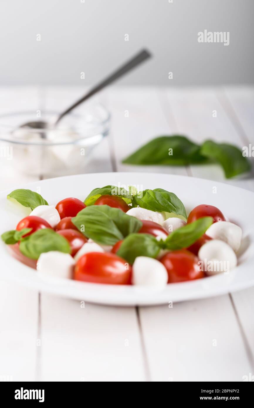 Fresh mozzarella cheese balls with cherry tomatoes and green basil isolated on white background