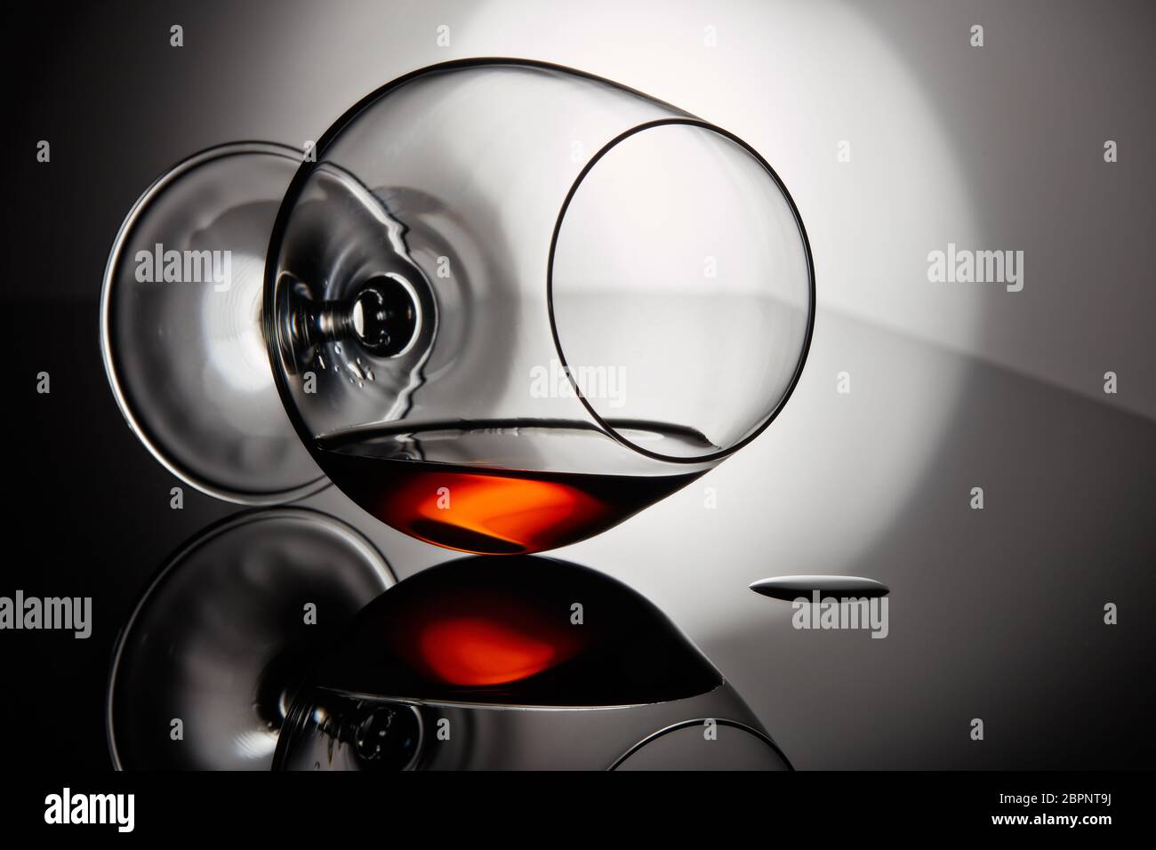 Snifter glass with cognac (brandy snifter, brandy bowl, cognac glass, or balloon) lying on a