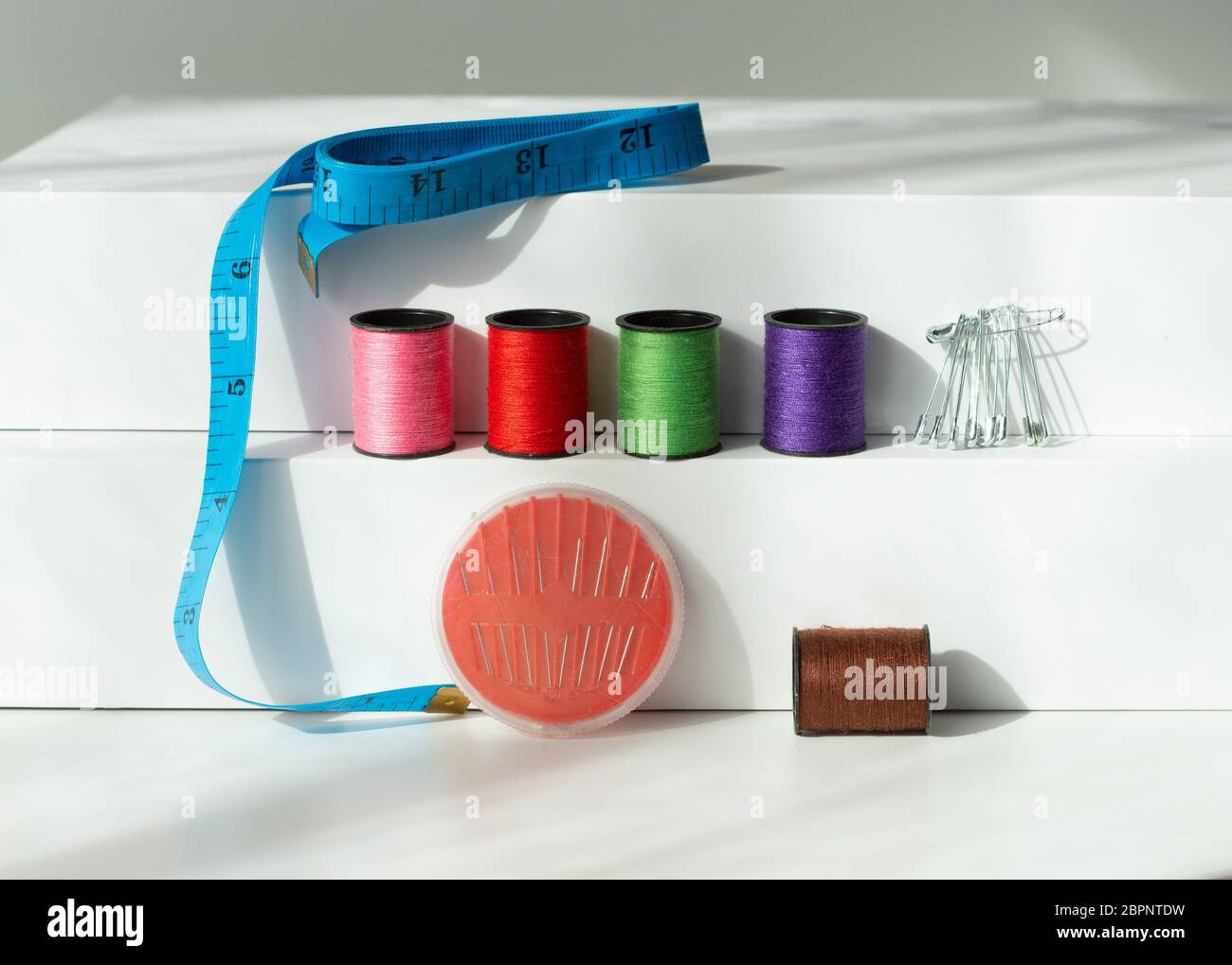 Creative composition with spools of colored threads and scissors. Sewing accessories, tailoring set. Stock Photo