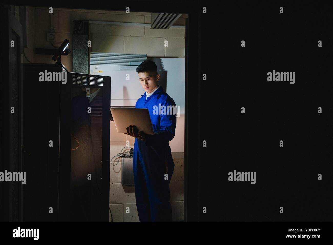 Trainee technician is working in the server room. Stock Photo