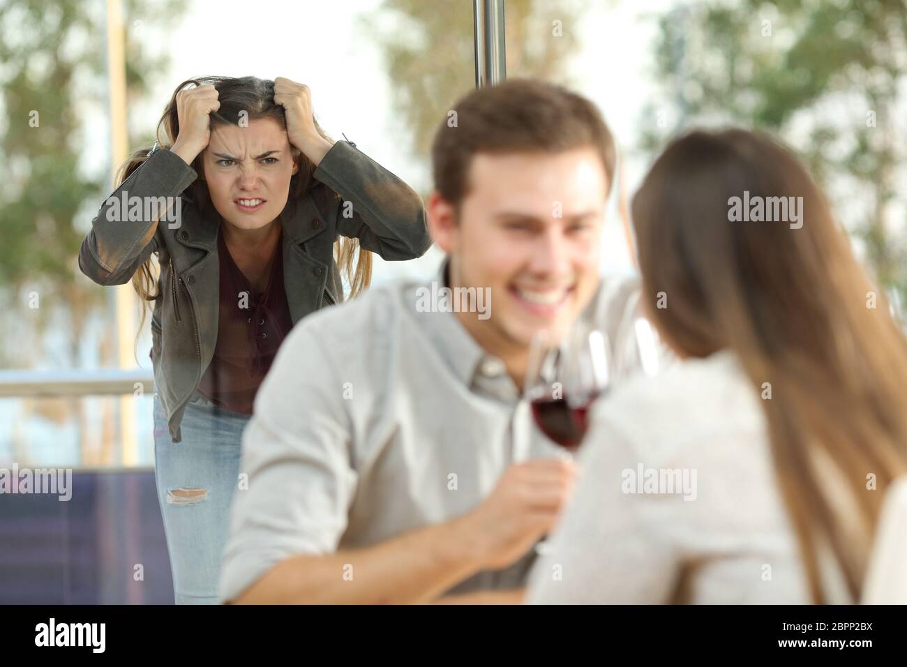 Disloyal boyfriend caught by his angry girlfriend dating with another girl in a restaurant Stock Photo