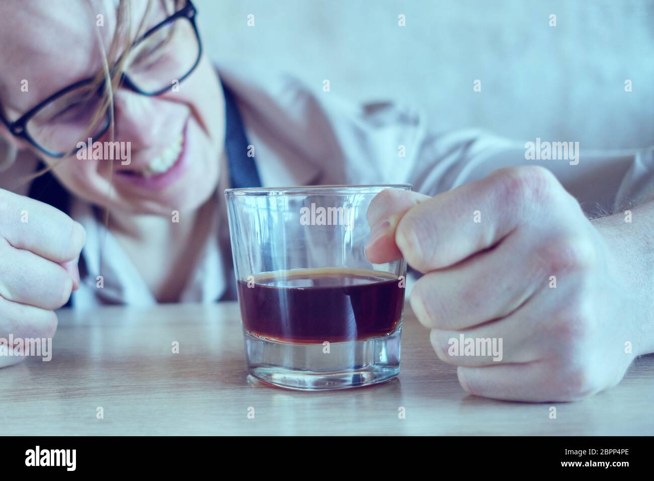 A drunk man in a shirt and tie is banging his fist on the table. Toned. Close up. Stock Photo