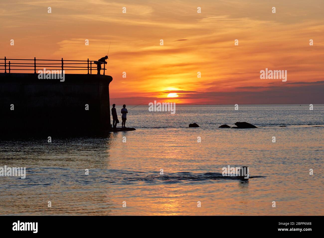 Hampton Pier, Herne Bay, Kent, UK. 19th May 2020: UK Weather. Sunset at Hampton Pier as anglers and a swimmer take advantage of the warm weather and calm conditions as the tide comes in. The next few days could see temperatures up to the high twenties. Credit: Alan Payton/Alamy Live News Stock Photo