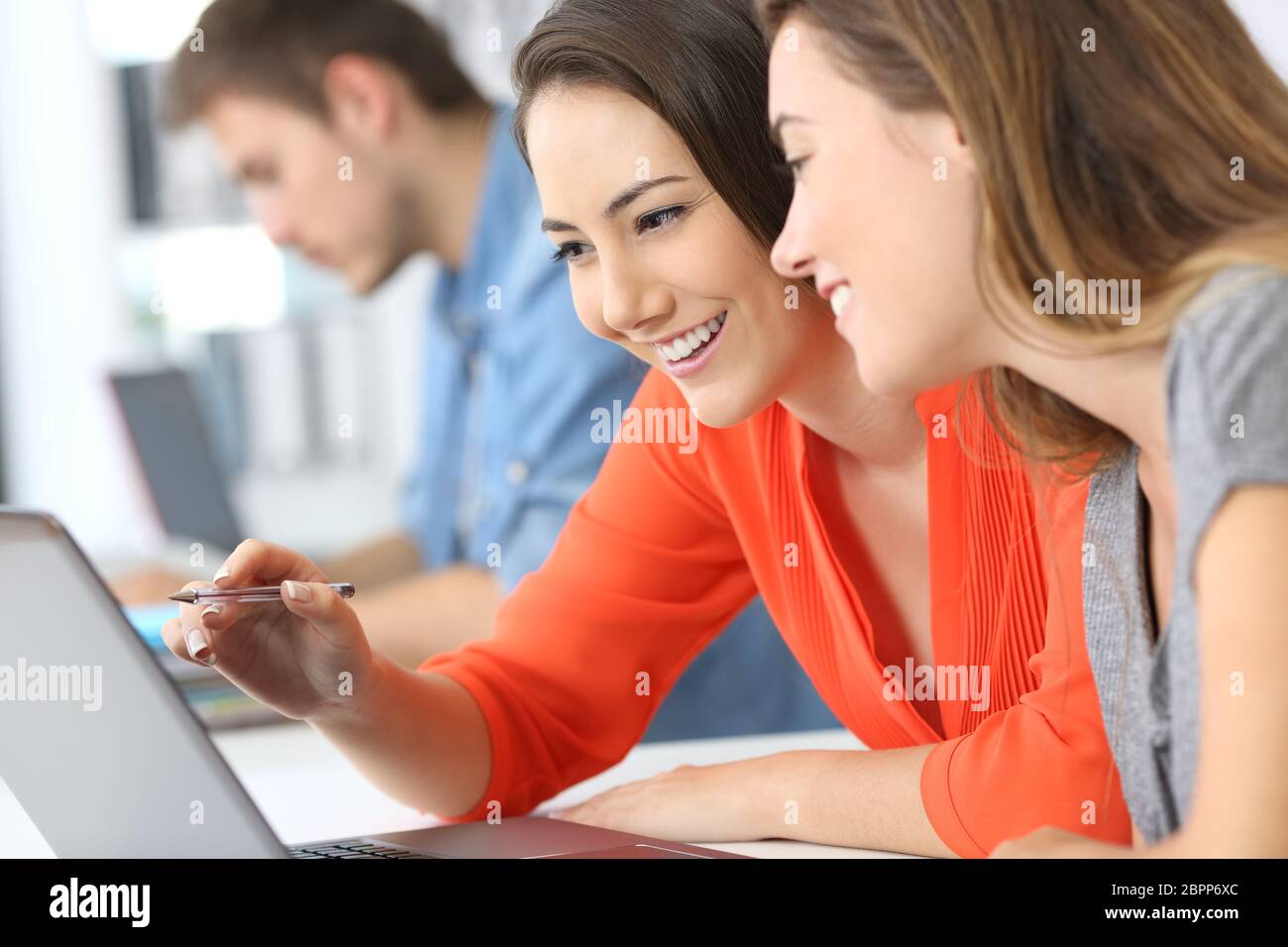 Two employees co-working on line with a laptop at office Stock Photo