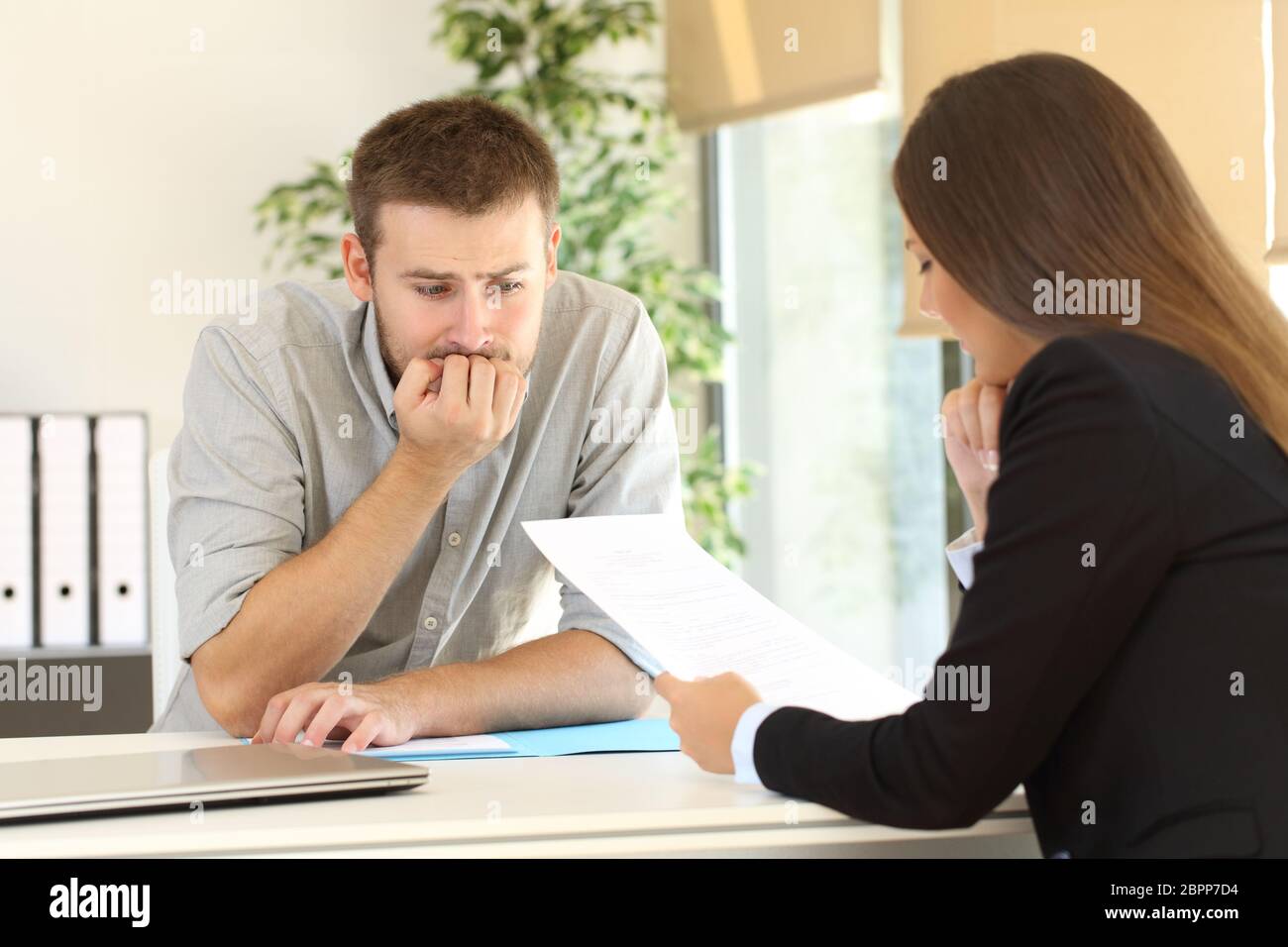 Nervous man looking how the interviewer is reading his resume during a job interview Stock Photo