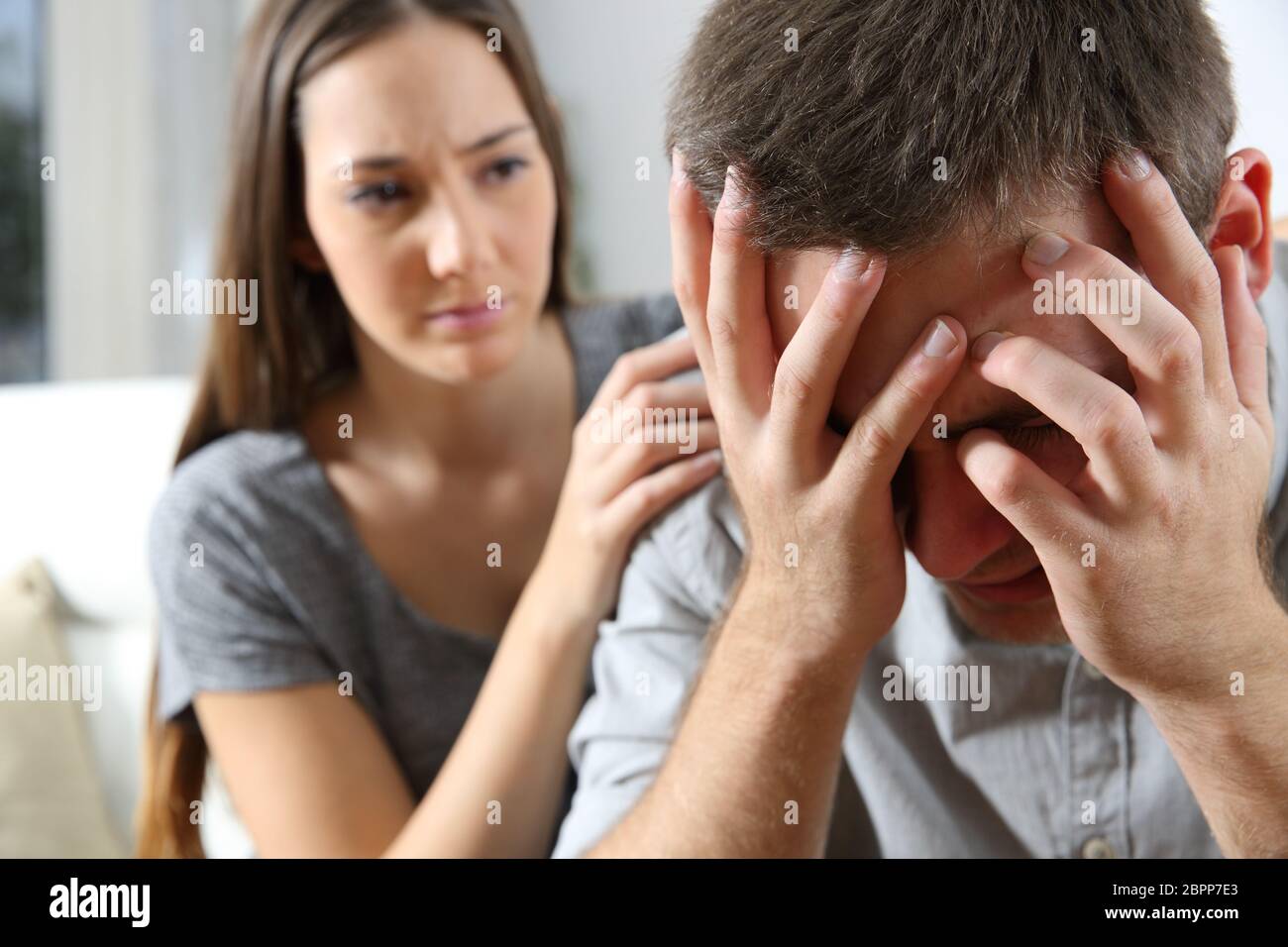 Sad man and a friend or girlfriend trying to console him at home ...