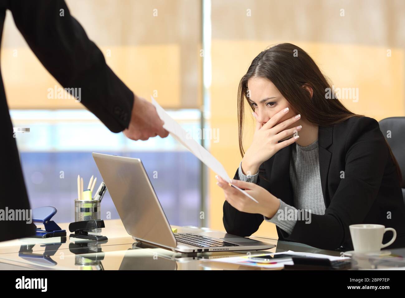 Worried businesswoman receiving a notification from a colleague in her workplace at office Stock Photo