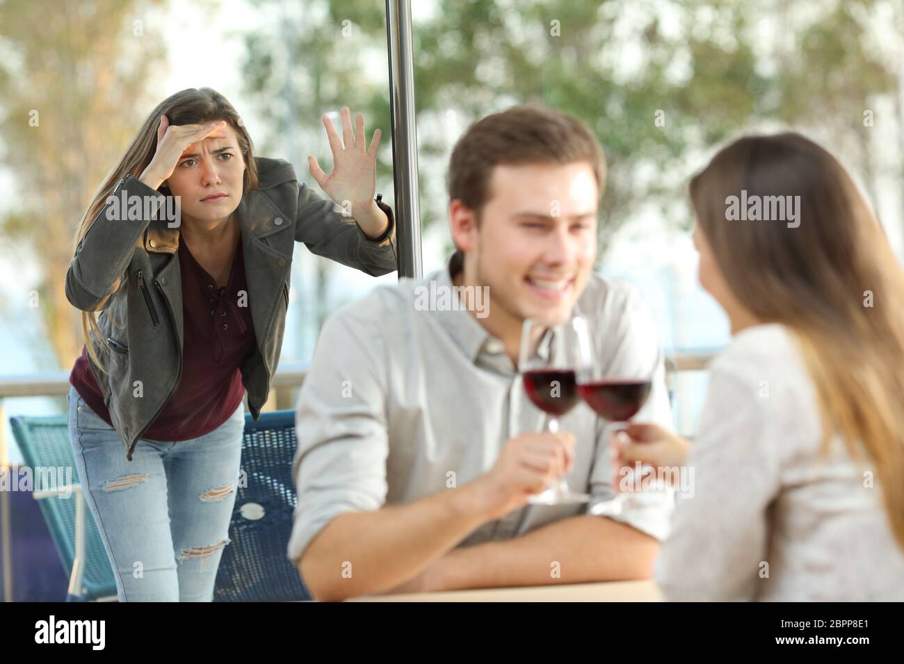 Stalker ex girlfriend spying on a couple in a coffee shop Stock Photo