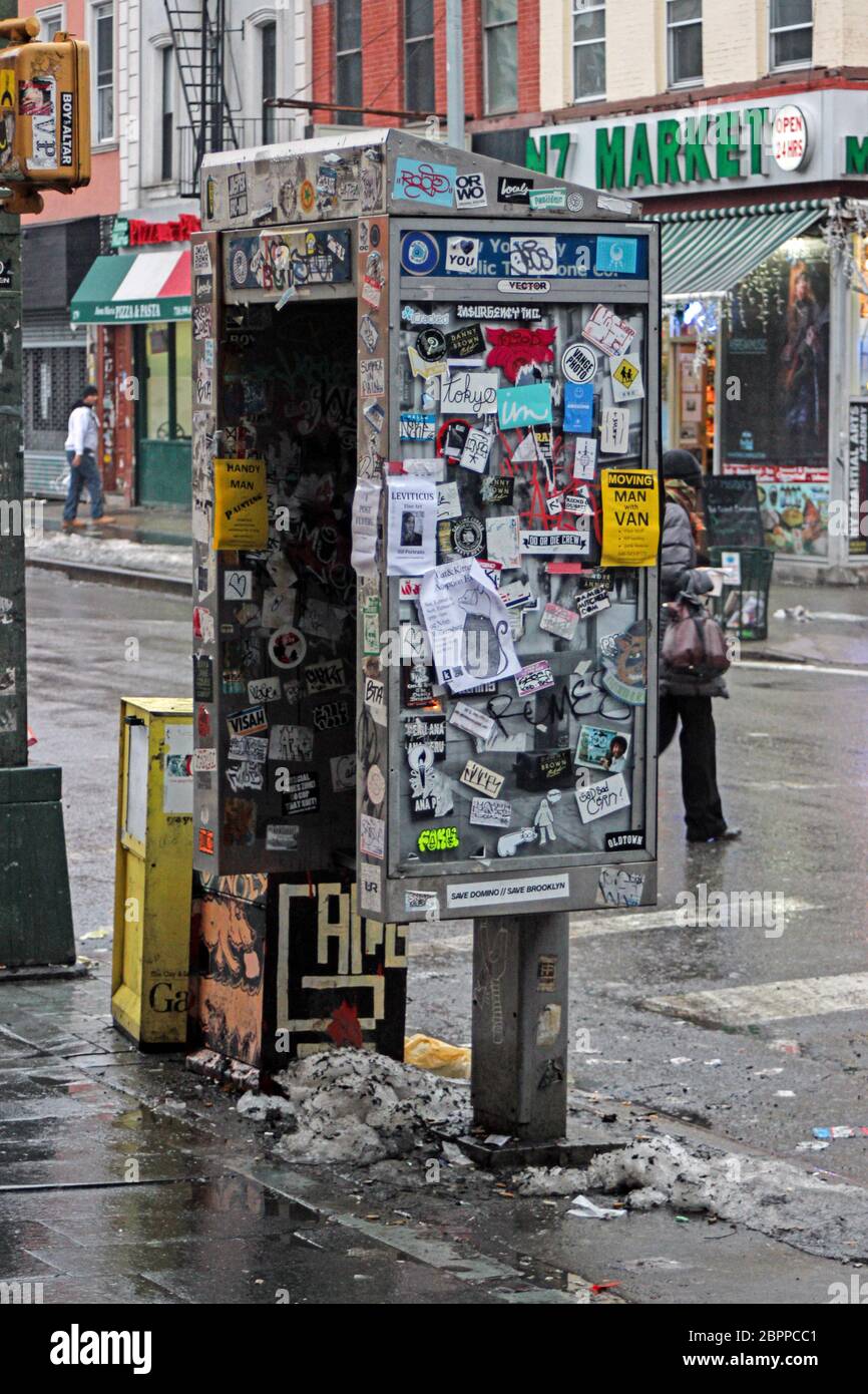 Telephone booth covered in stickers and flyers in Williamsburg district