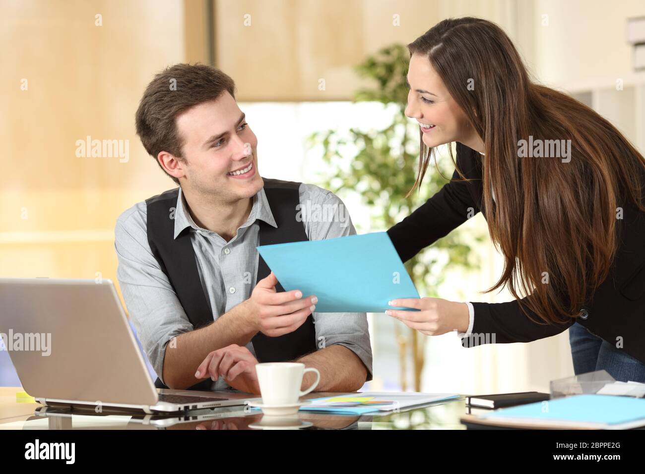 Happy executive or secretary giving documents to a businessman in a ...